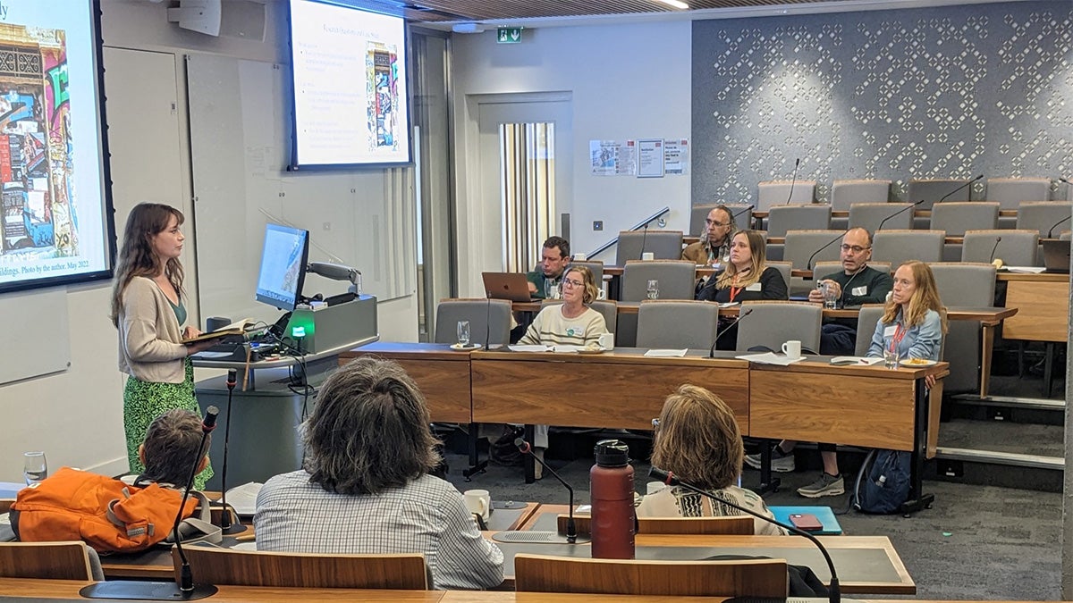 A presenter speaking to adults in a college classroom.