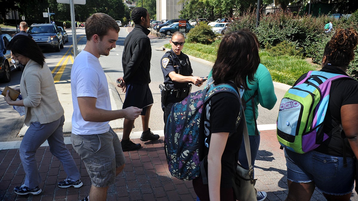 Students crossing a crosswalk on South Road as a police officer directs traffic.