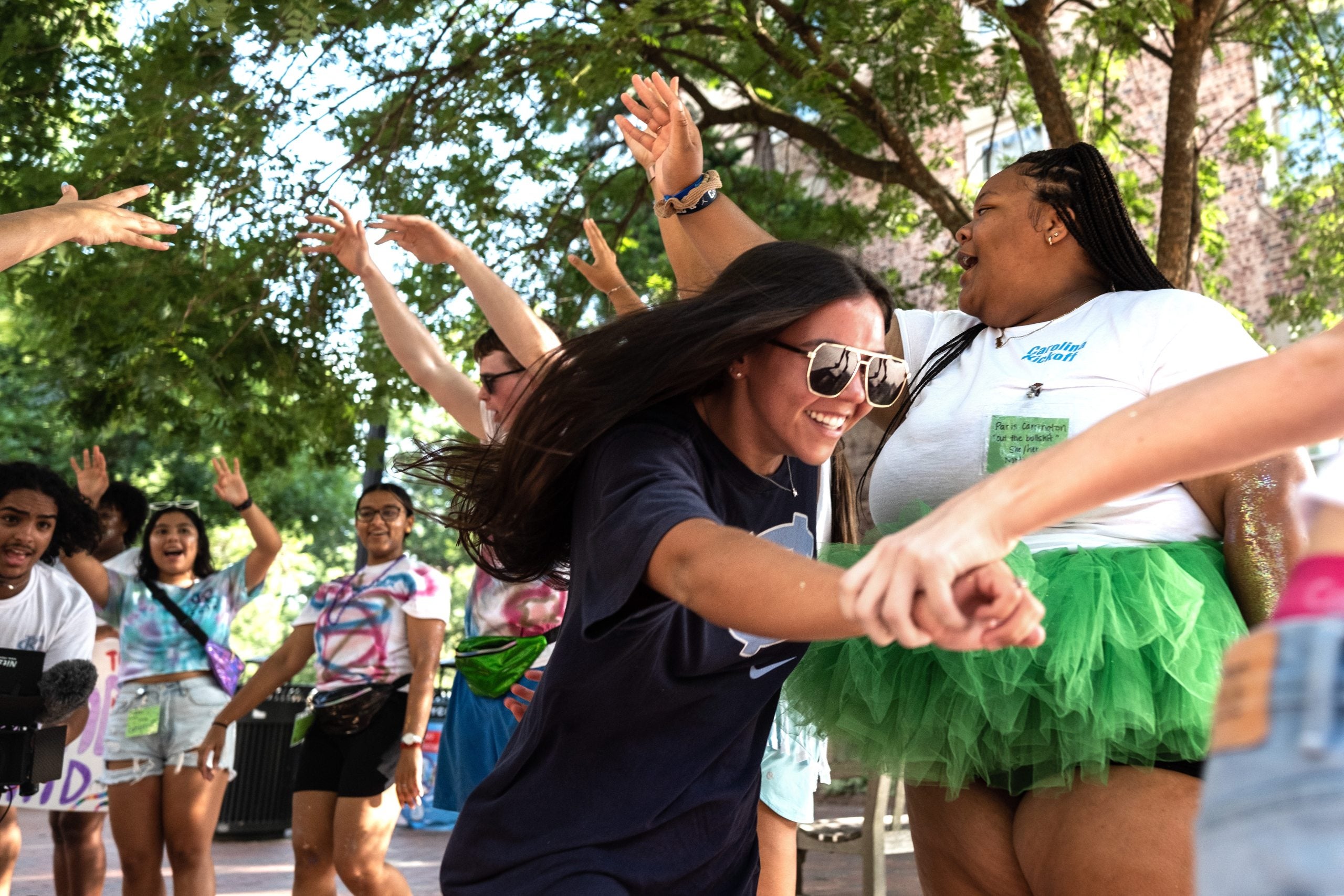A student holding another's hand as she as she runs during a welcome activity on the campus of UNC-Chapel Hill.