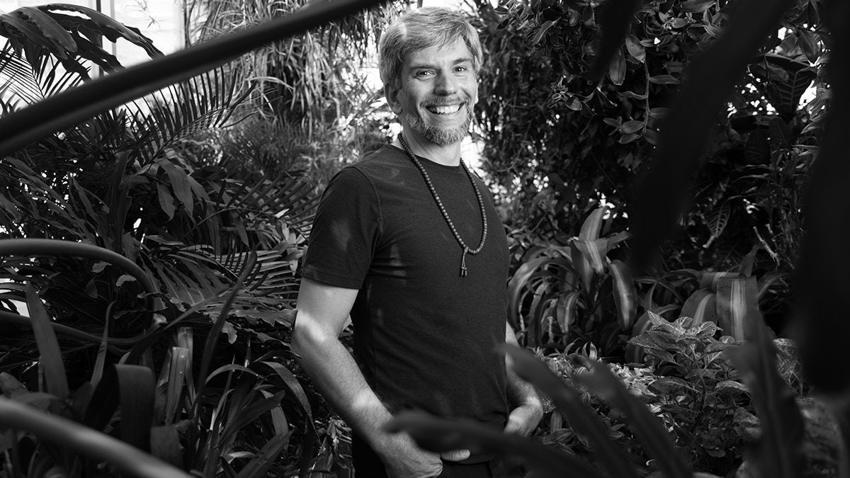 György “Hínár” Schrader Polczer stands in front of several plants and smiles at the camera.