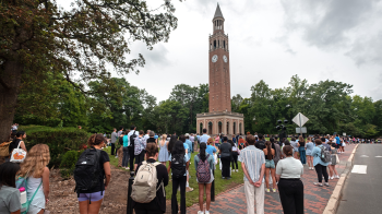 A crowd of people gathered at a bell tower for a remembrance.