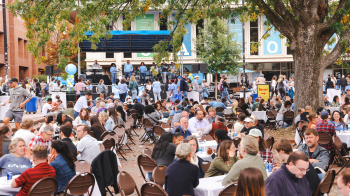 Image of a large crowd of people sitting at tables outside and eating lunch in the Pit on the campus of UNC-Chapel Hill as part of Employee Appreciation Day.