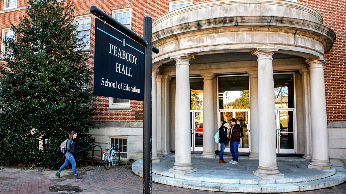 A handful of students walk around the School of Education building.