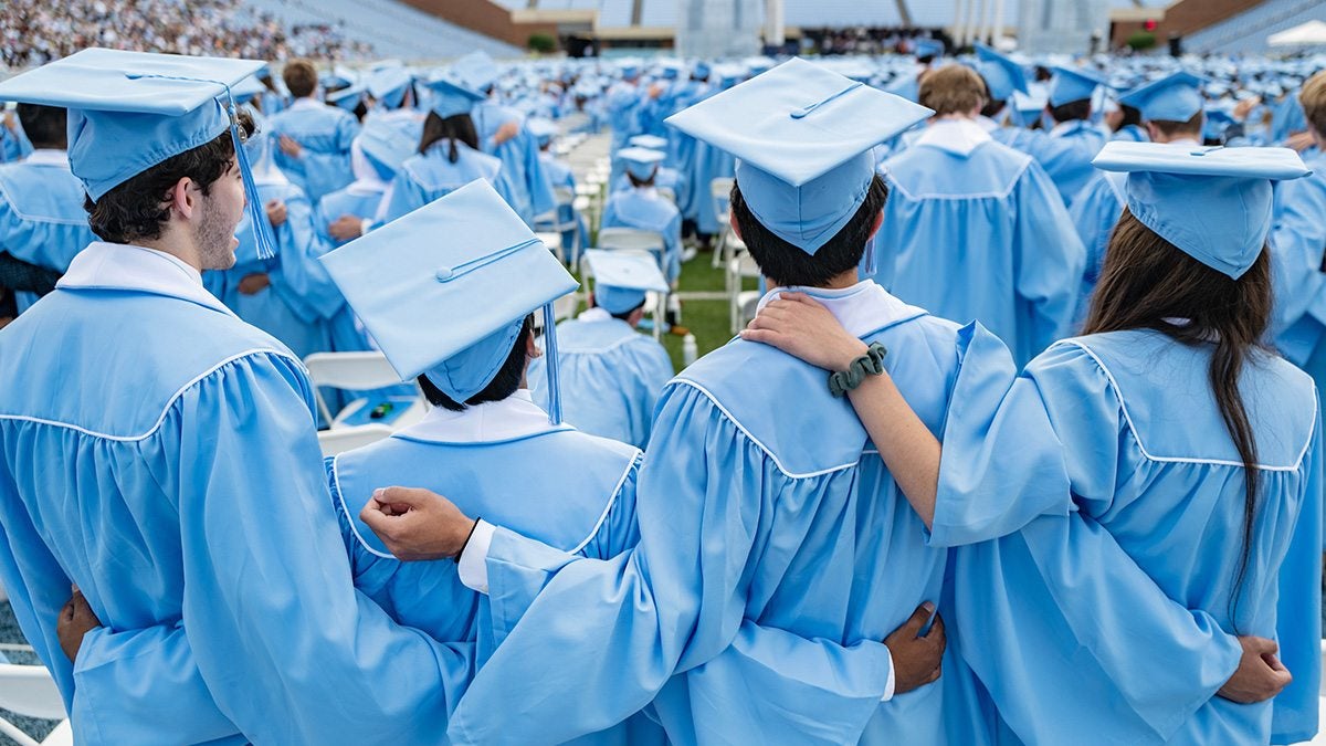 Large group of graduates standing with their backs facing the camera