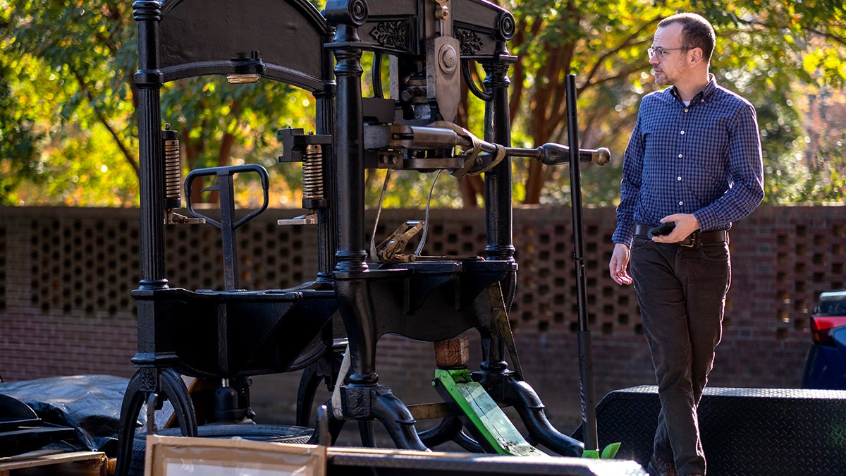 A man looks at the printing press as it is about to get unloaded.