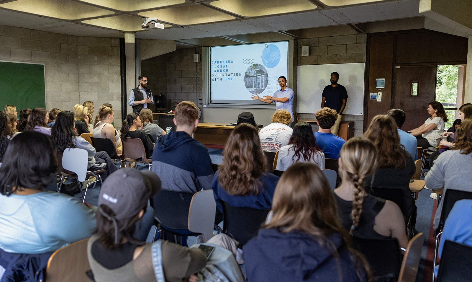 A presenter giving a PowerPoint presentation to a group of students in a large classroom.