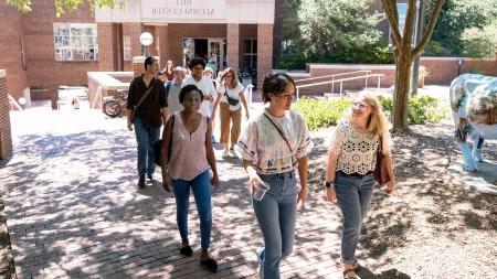 A group of graduate students walking on a brick pathway on the campus of UNC-Chapel Hill.