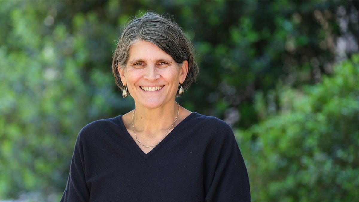 Jill Hamm in front of greenery wearing earrings and a black shirt.