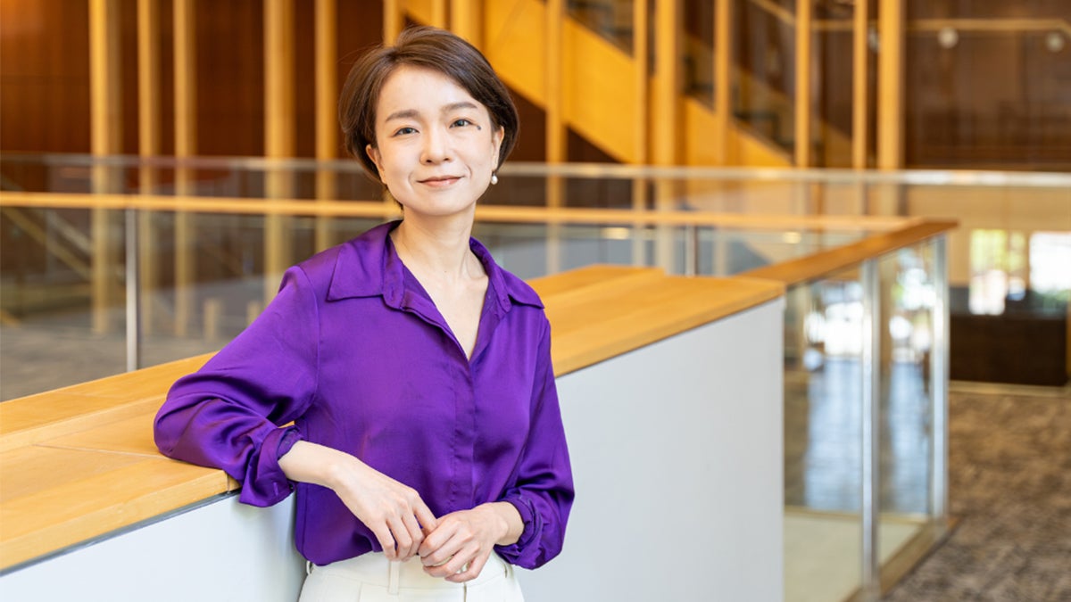A straight on headshot of Luoyi Cai slightly leaning on a railing.