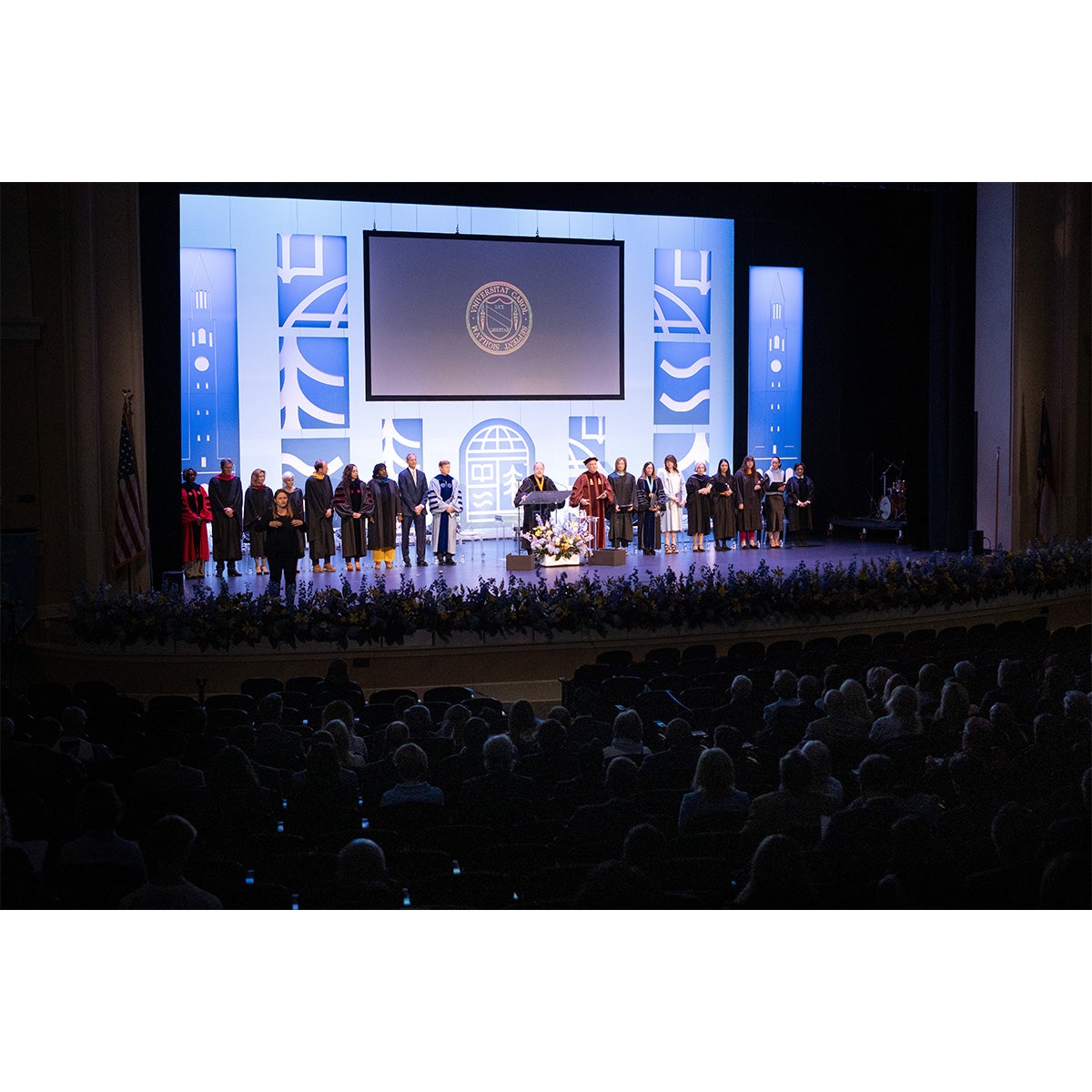 University leaders on stage at Memorial Hall during UNC-Chapel Hill's University Day celebration that included the installation of Lee H. Roberts. UNC System President Peter Hans is speaking from a podium.