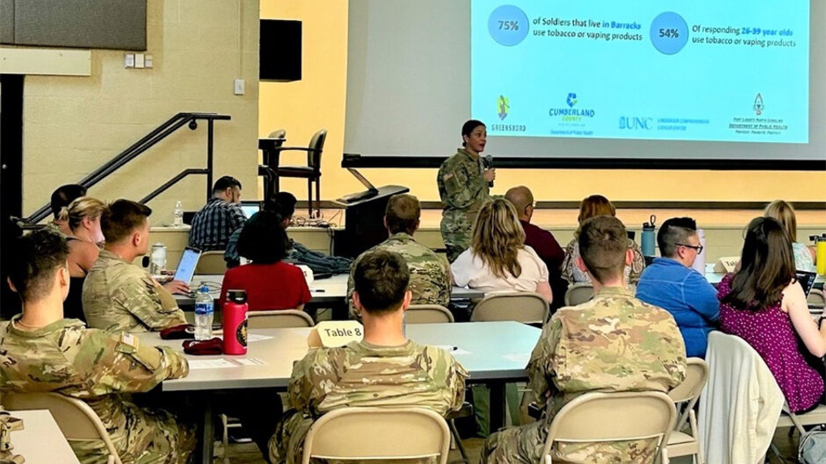 A U.S.A. soldier, in uniform, addresses health concern and prevention to a group of soldiers.