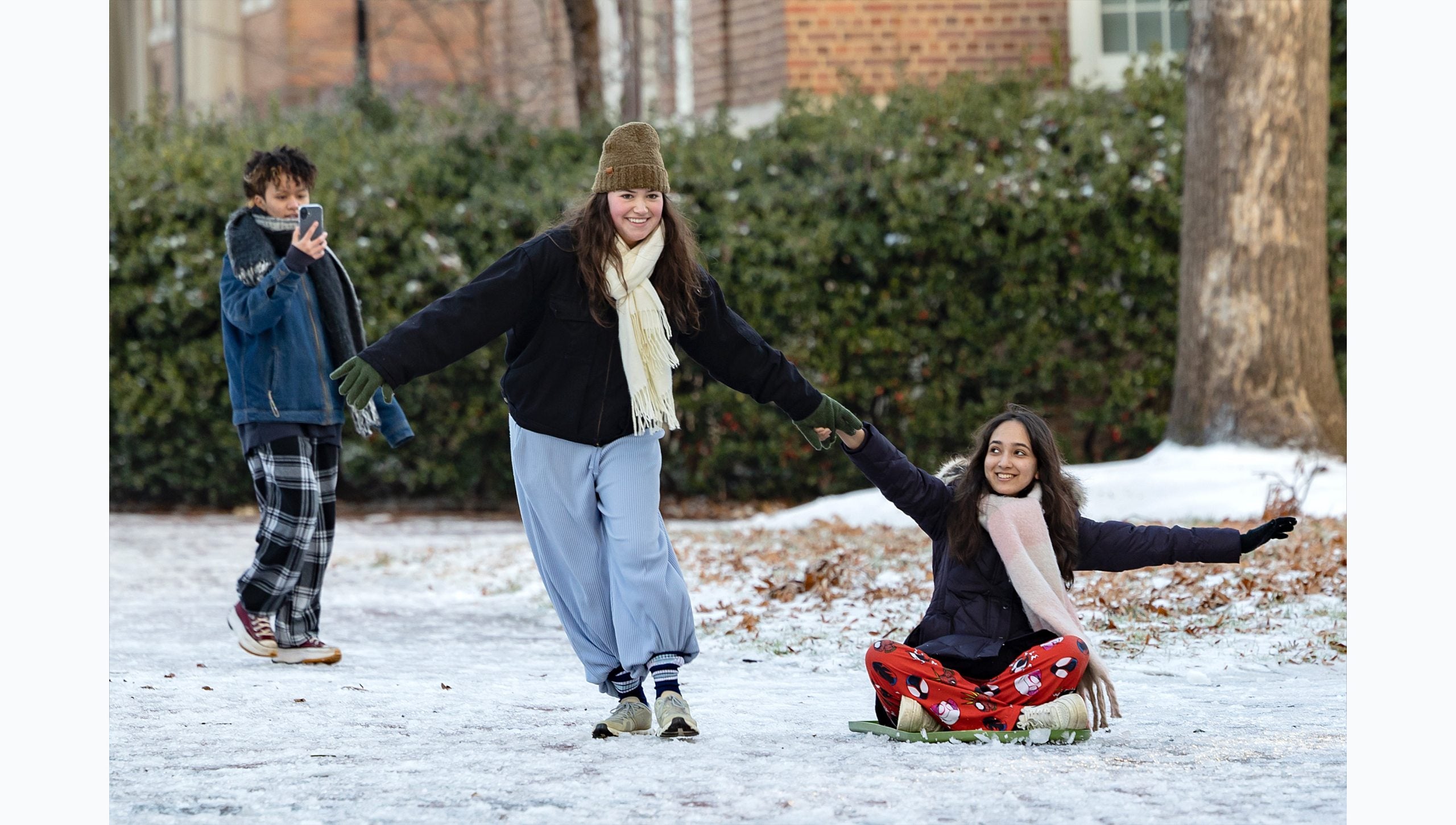 One student pulling another on a sled on the snowy campus of U.N.C Chapel Hill.