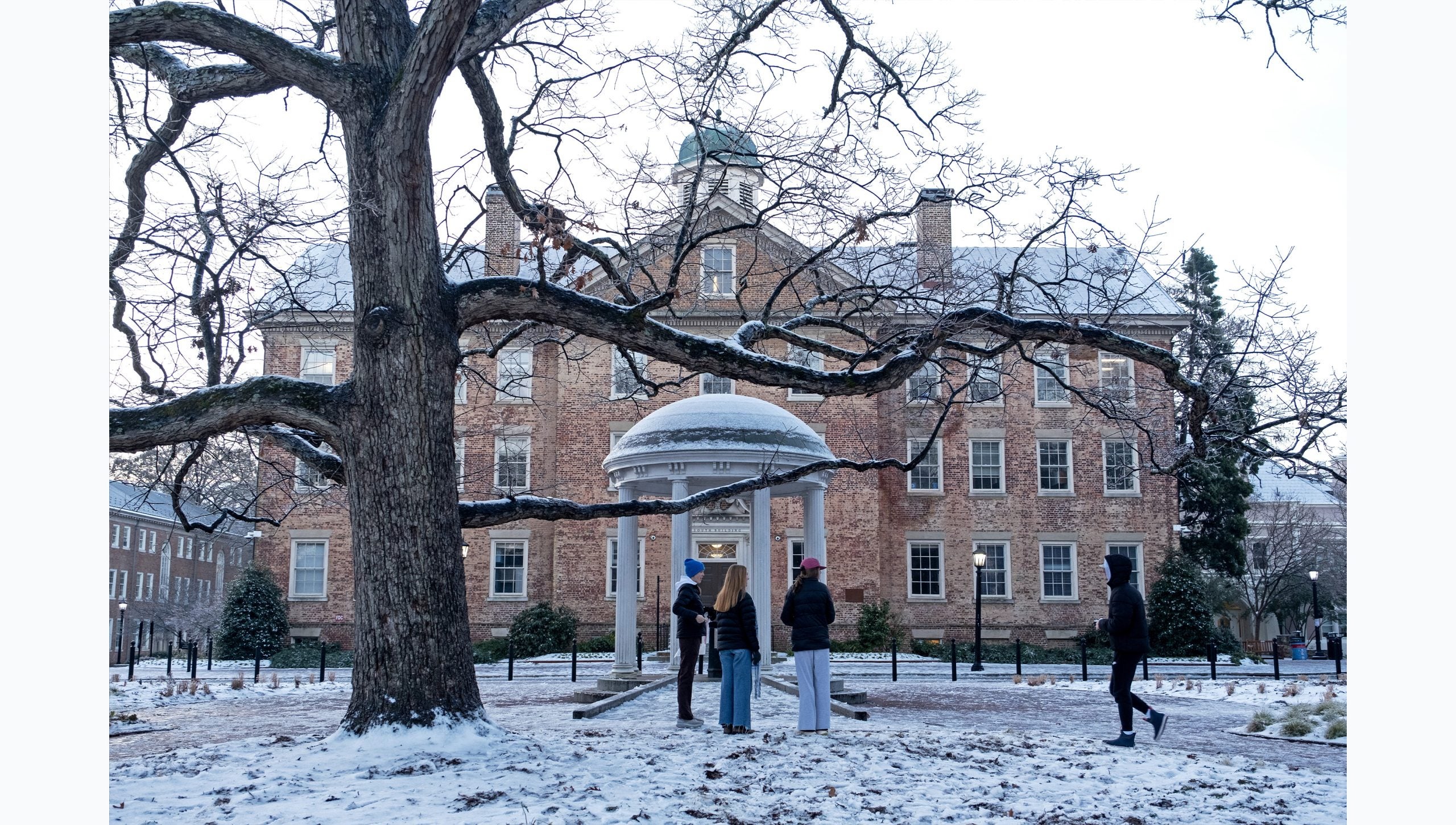 Students hanging out by the Old Well on a snowy day on the campus of U.N.C Chapel Hill.