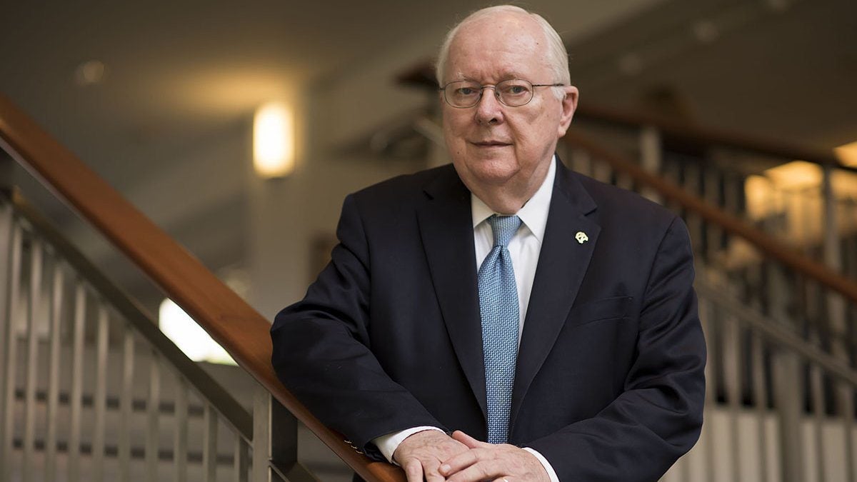 Joe Ferrell wearing suit and posing near staircase.