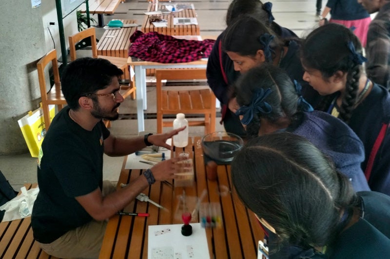 A researcher, Abel Abraham, speaking to students at a booth at a university about his research.