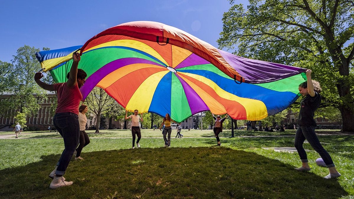 Students throwing up rainbow colored sheet in the air.