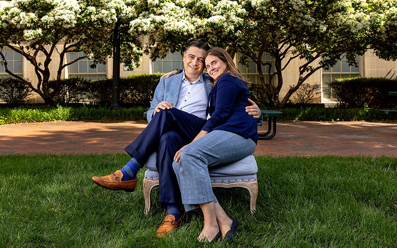 Dr. John Vavalle and Emily Sickbert-Bennett Vavalle sit together in a blue chair on Carolina's campus