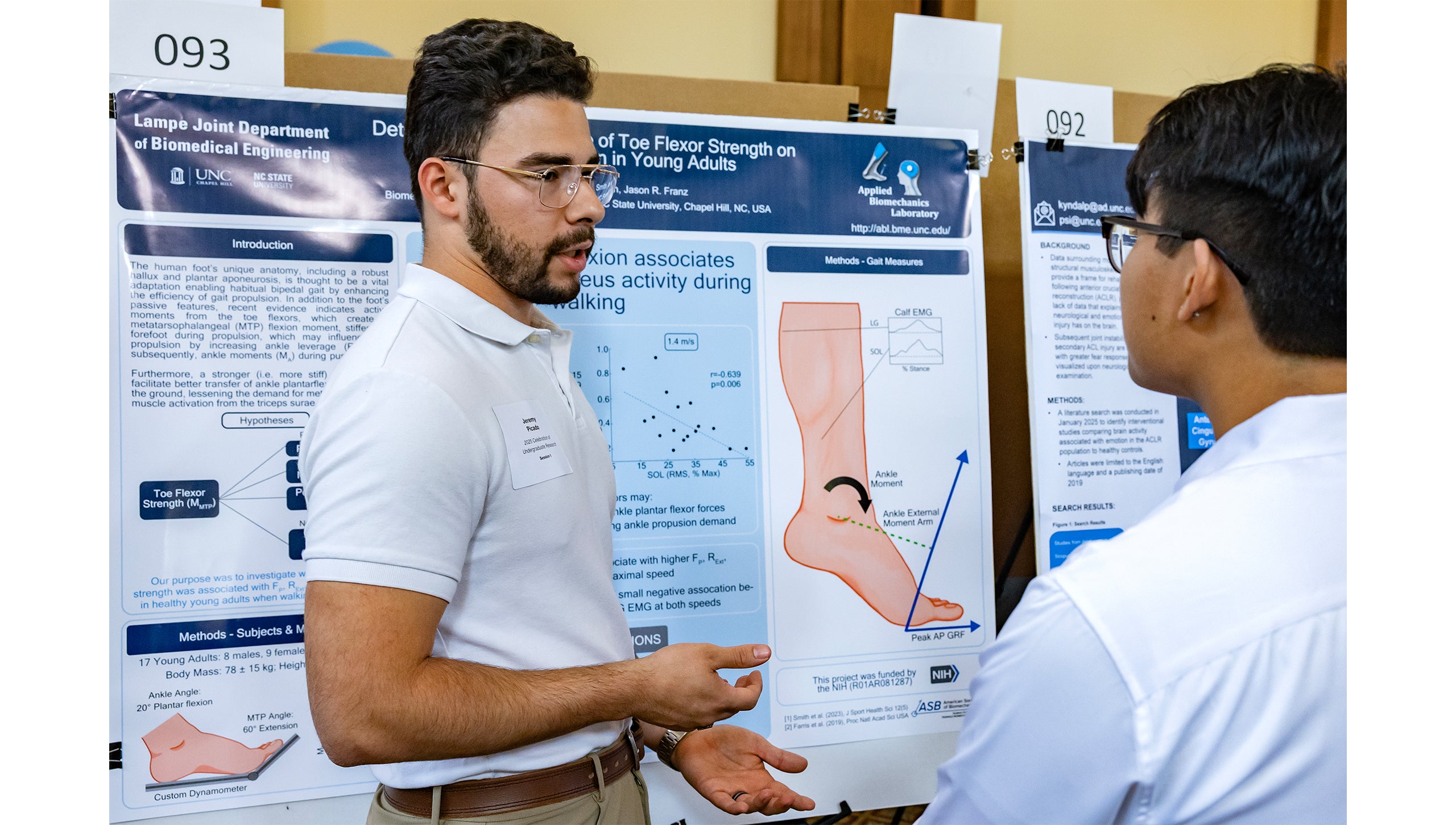 A student stands by a poster explaining research at the Celebration of Undergraduate Research