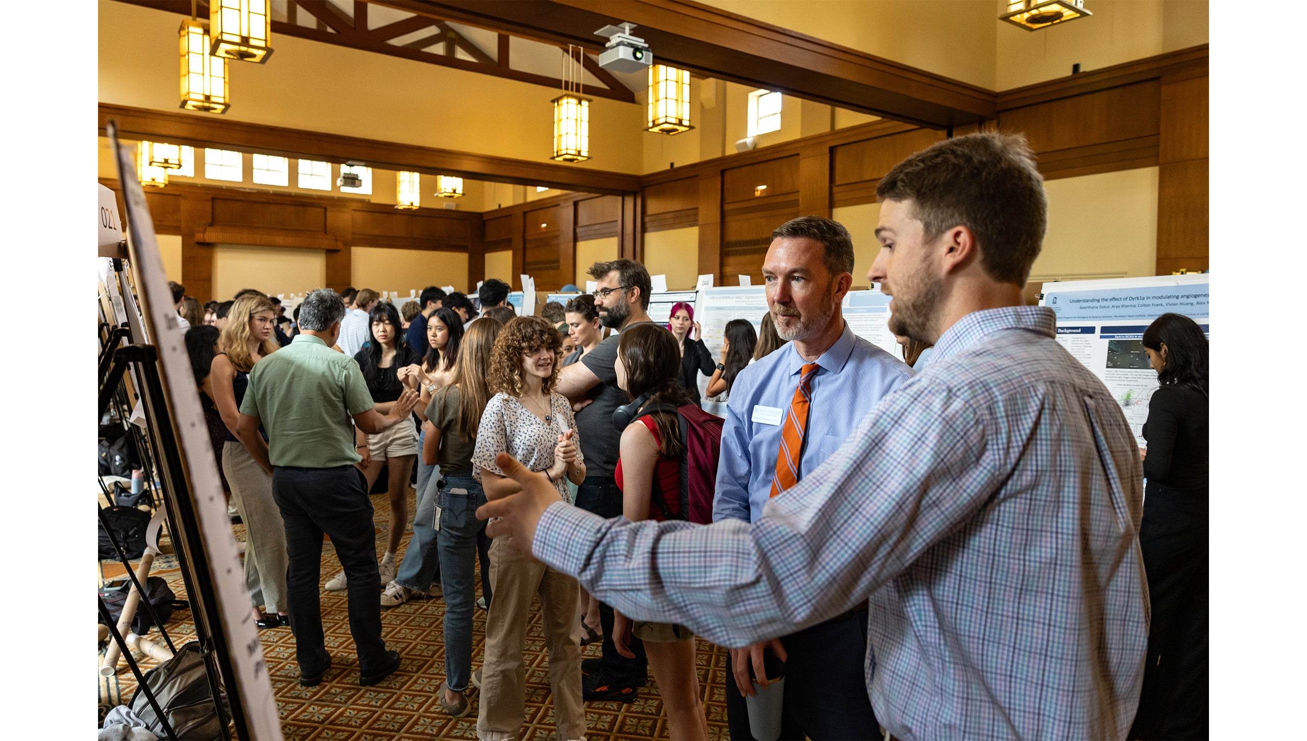 A student explains research to onlookers during the Celebration of Undergraduate Research