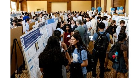 Attendees mingle by posters at the Celebration of Undergraduate Research