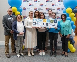 Group of people standing in front of balloons with sign that reads "POV Challenge".
