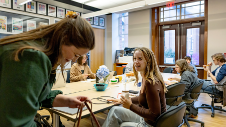 Annabel Dougherty laughing with students while sitting in transfer student lounge.