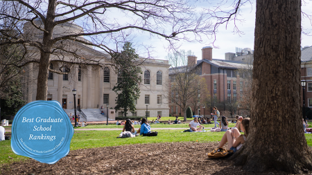 Students sitting on the lawn of Polk Place on UNC-Chapel Hill with Wilson Library and other academic buildings seen in the bacgkround. Atop the image is a Carolina Blue ribbon graphic reading: 