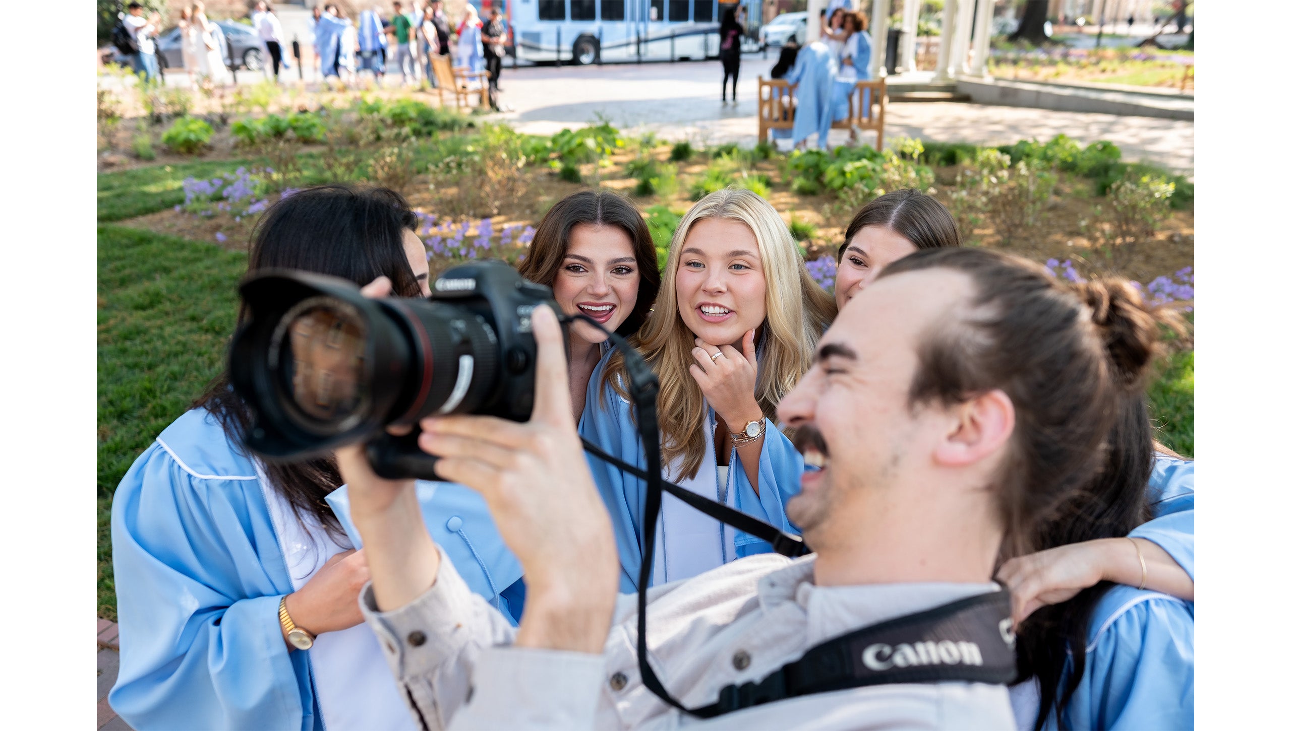 Graduates look at a photo on a photographer's camera