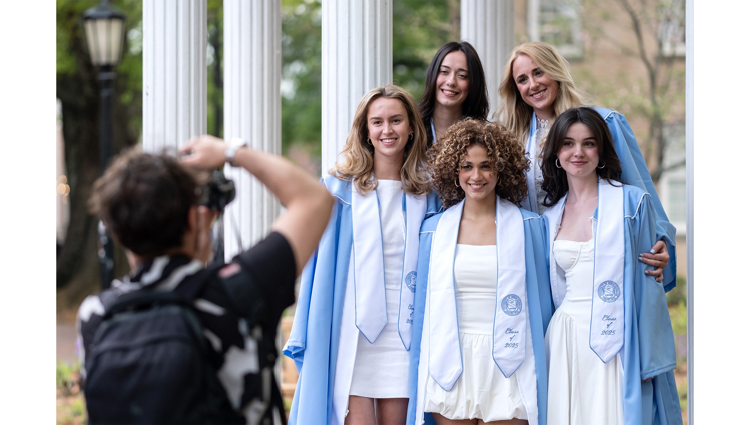 Graduates pose for a photo in front of the Old Well