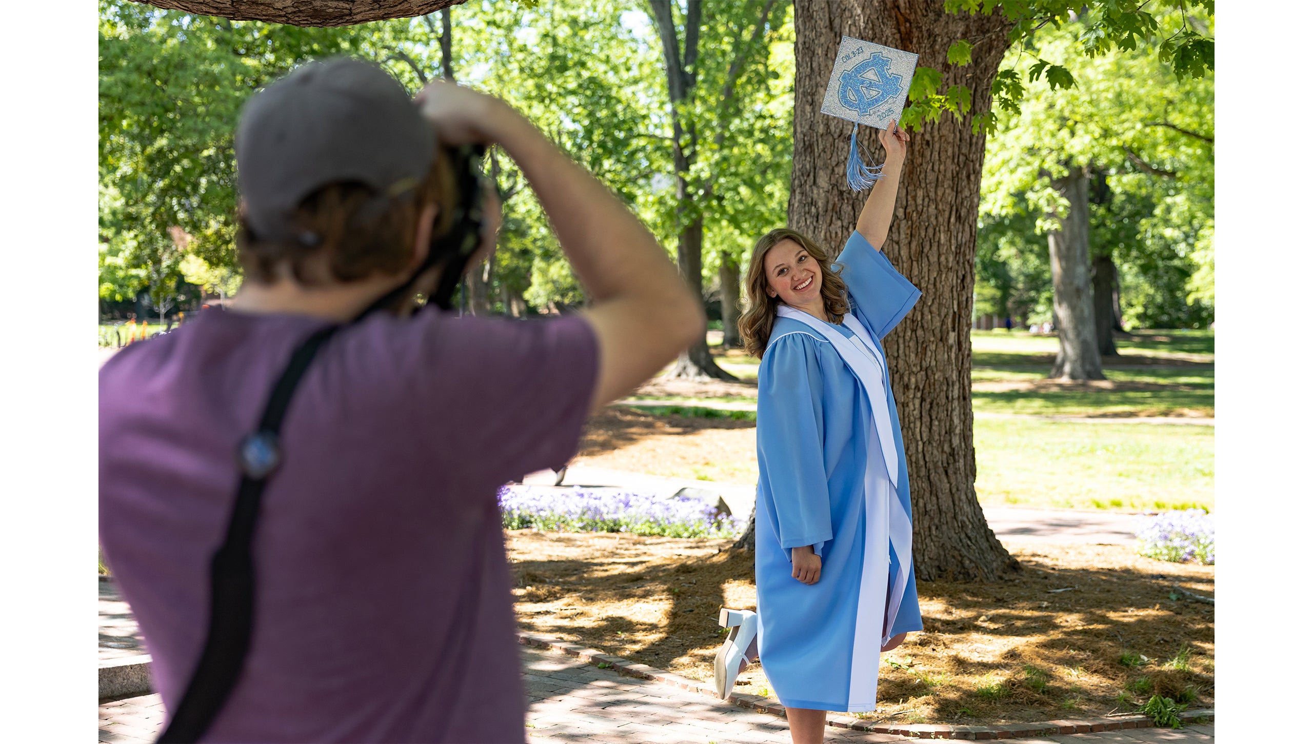 A graduate holds her cap up while posing for a photo