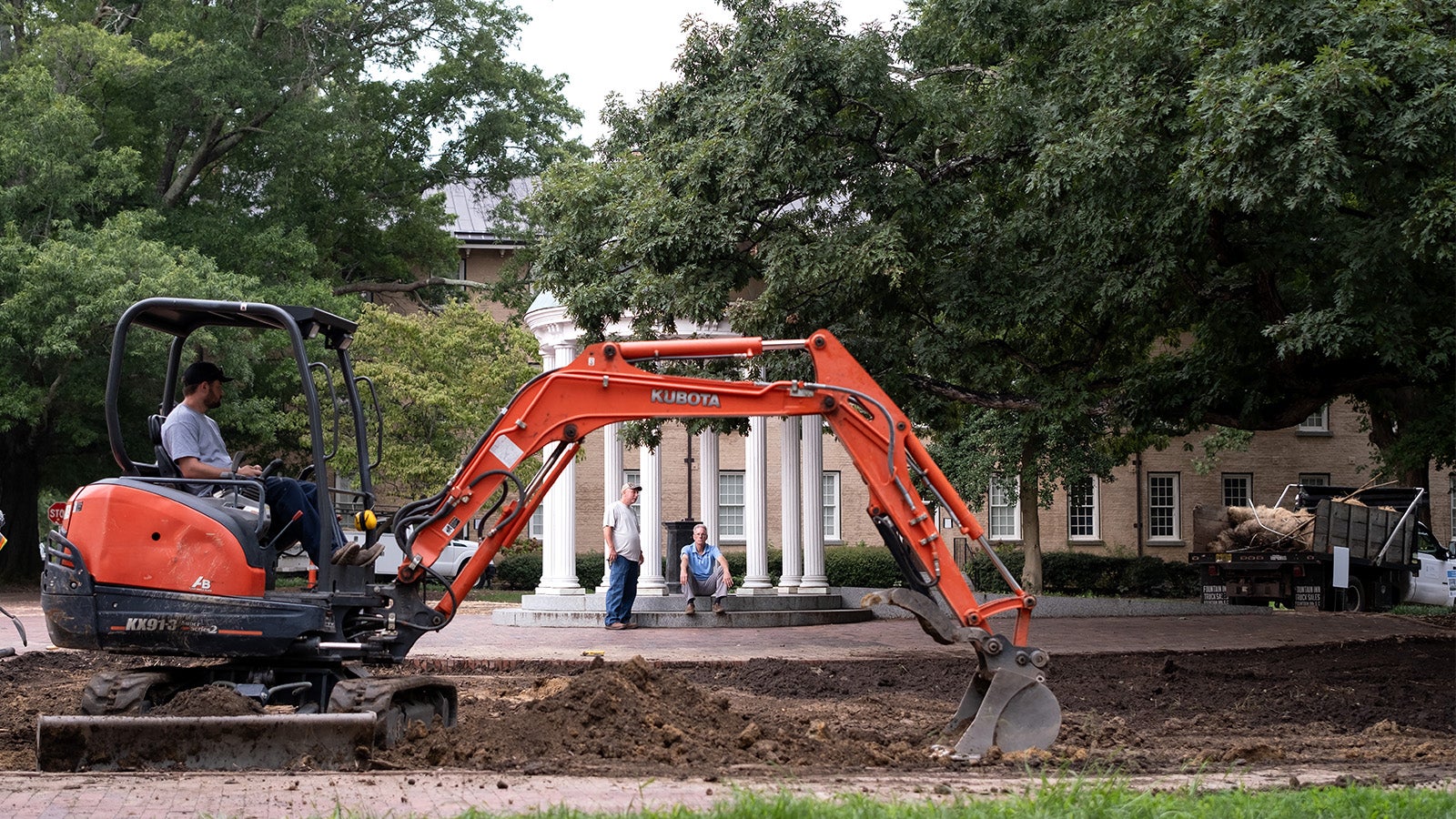 A bulldozer sits in front of the Old Well during a landscaping project.