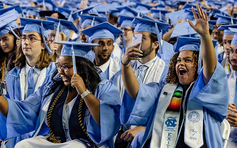 Graduates cheer and take photos at Kenan Stadium during 2024 Spring Commencement
