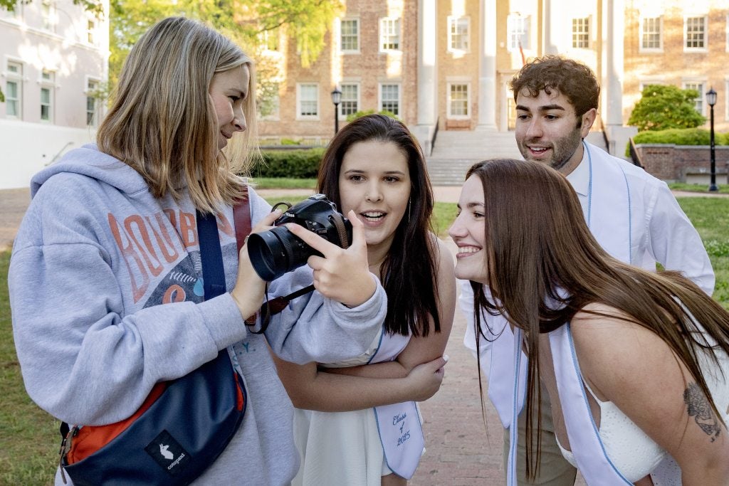 Samantha Lewis showing Shaena Riddles, Brittany Harrelson and Nick Clementi a photo she just made of them on the zoom focus of her camera.