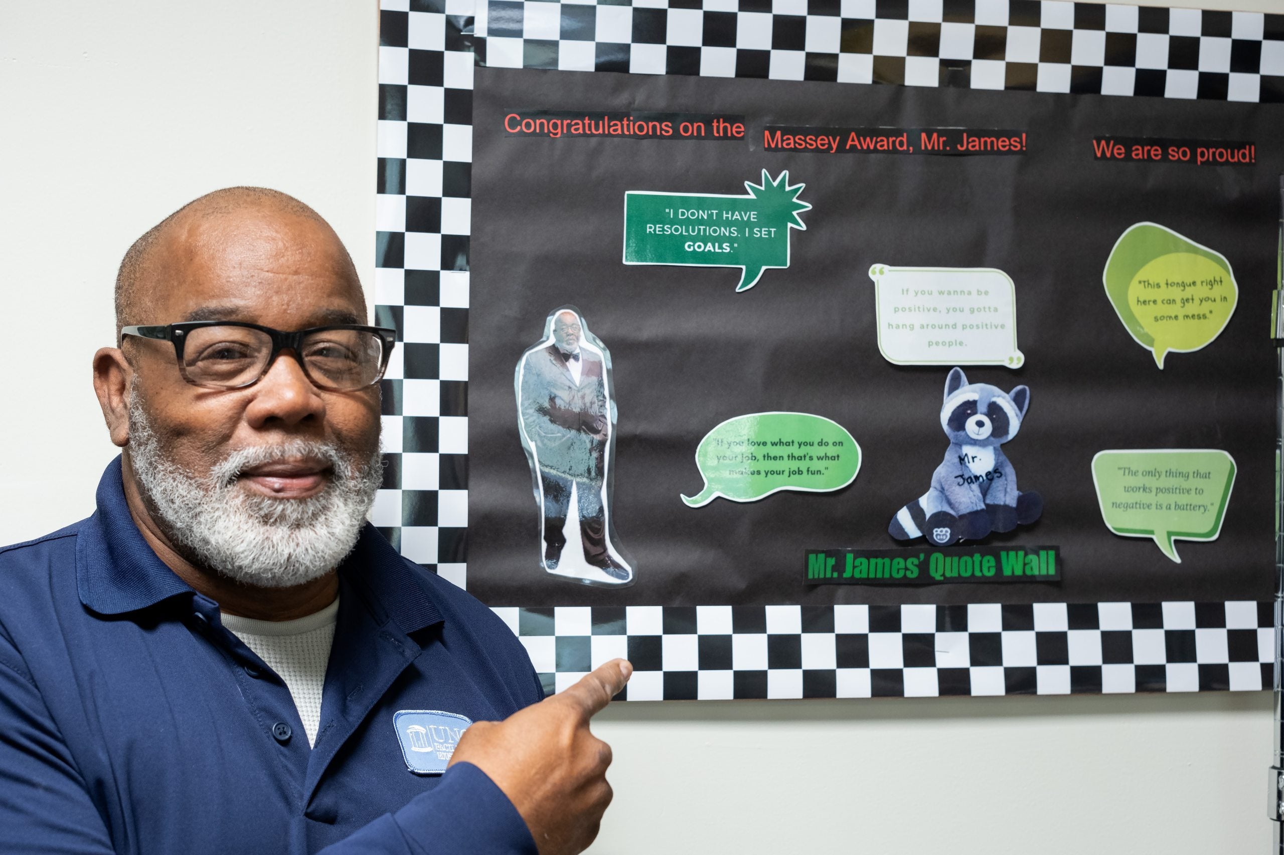 James Glass pointing at his quote wall.