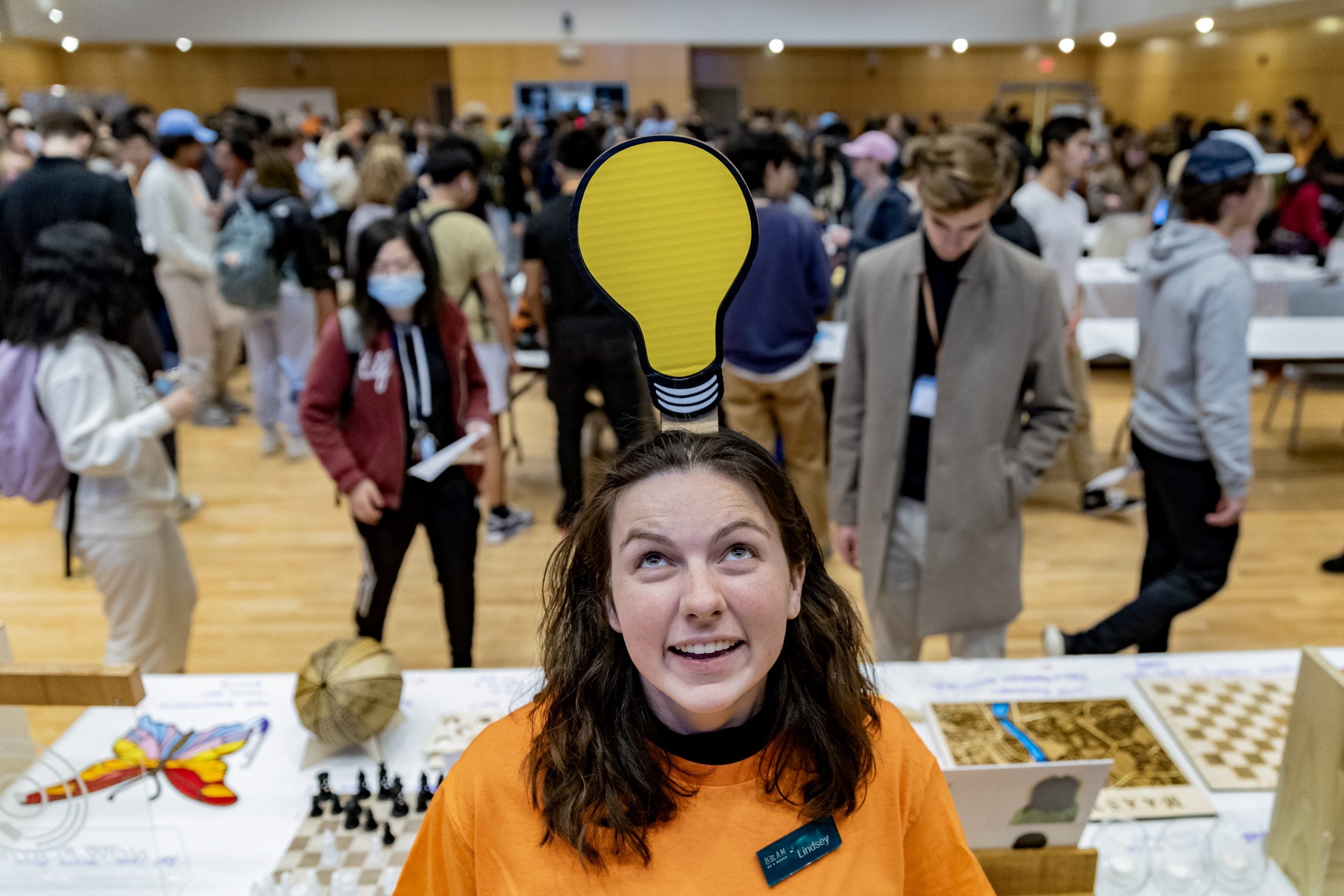 A BeAM worker poses for a photo with a light bulb over their head during the BeAM MakerFest event
