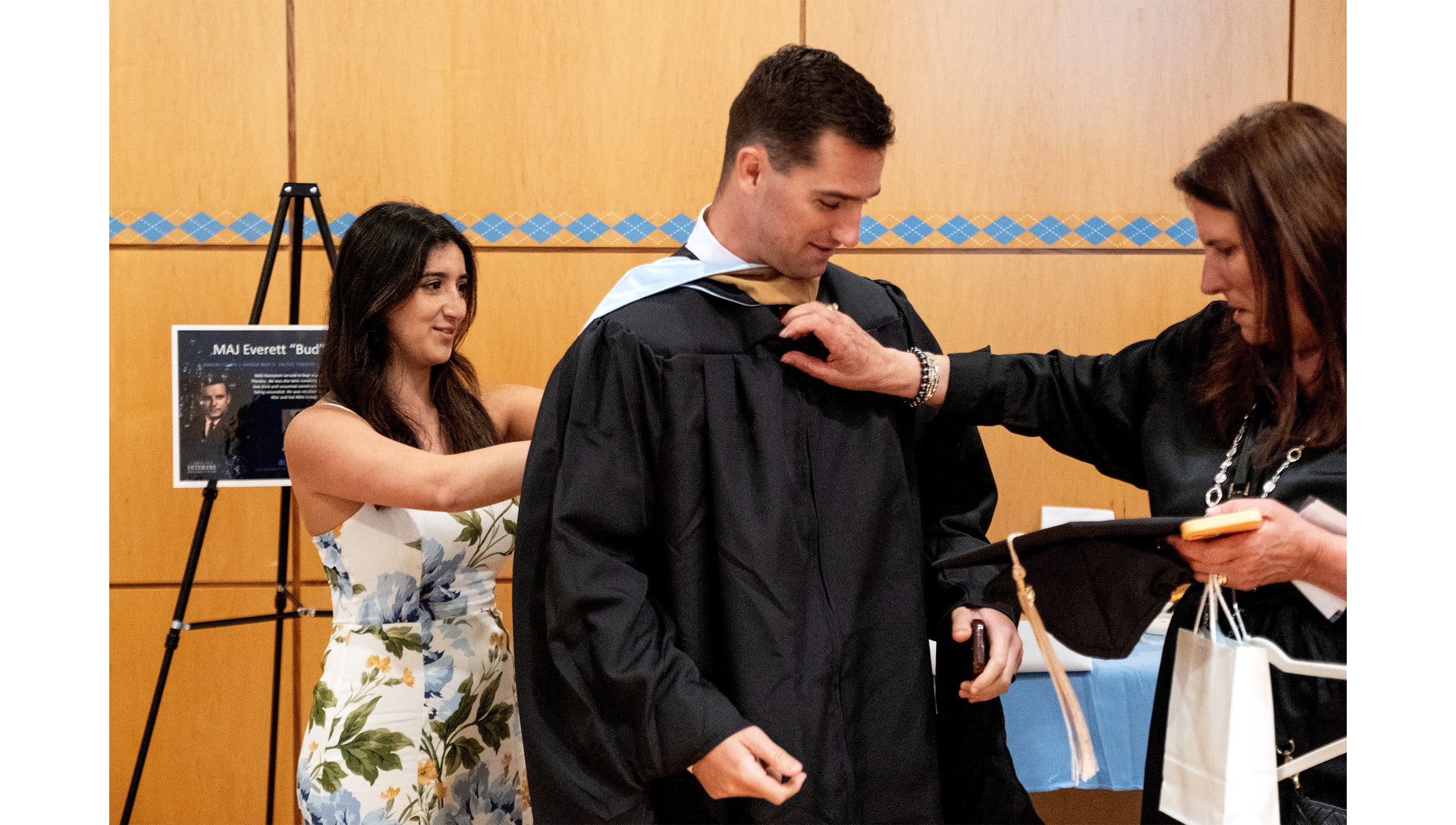 Family members dust off a graduate's gown at the Red, White and Carolina Blue Graduation