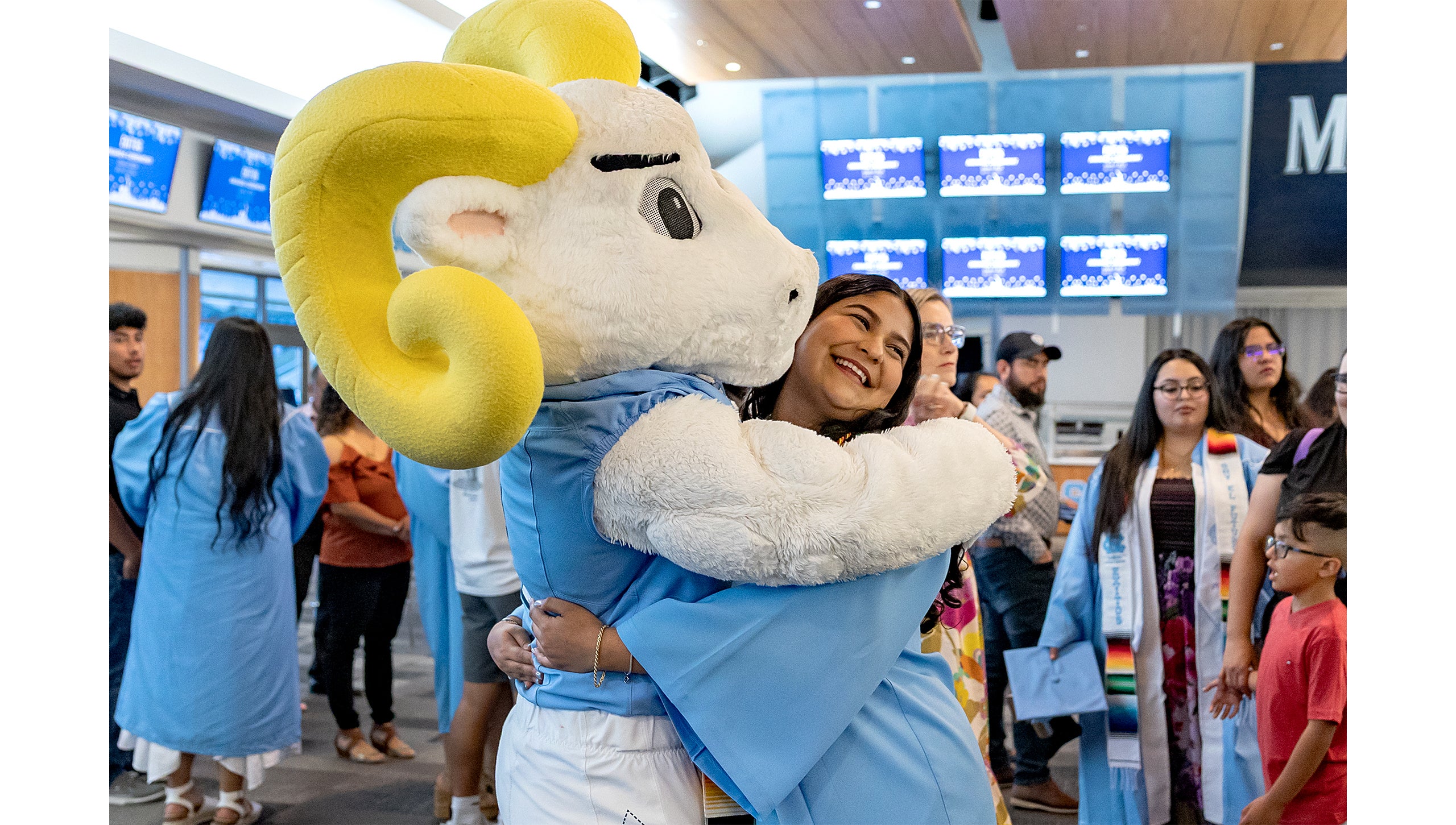 Rameses hugs a graduate at the Exitos Awards Ceremony