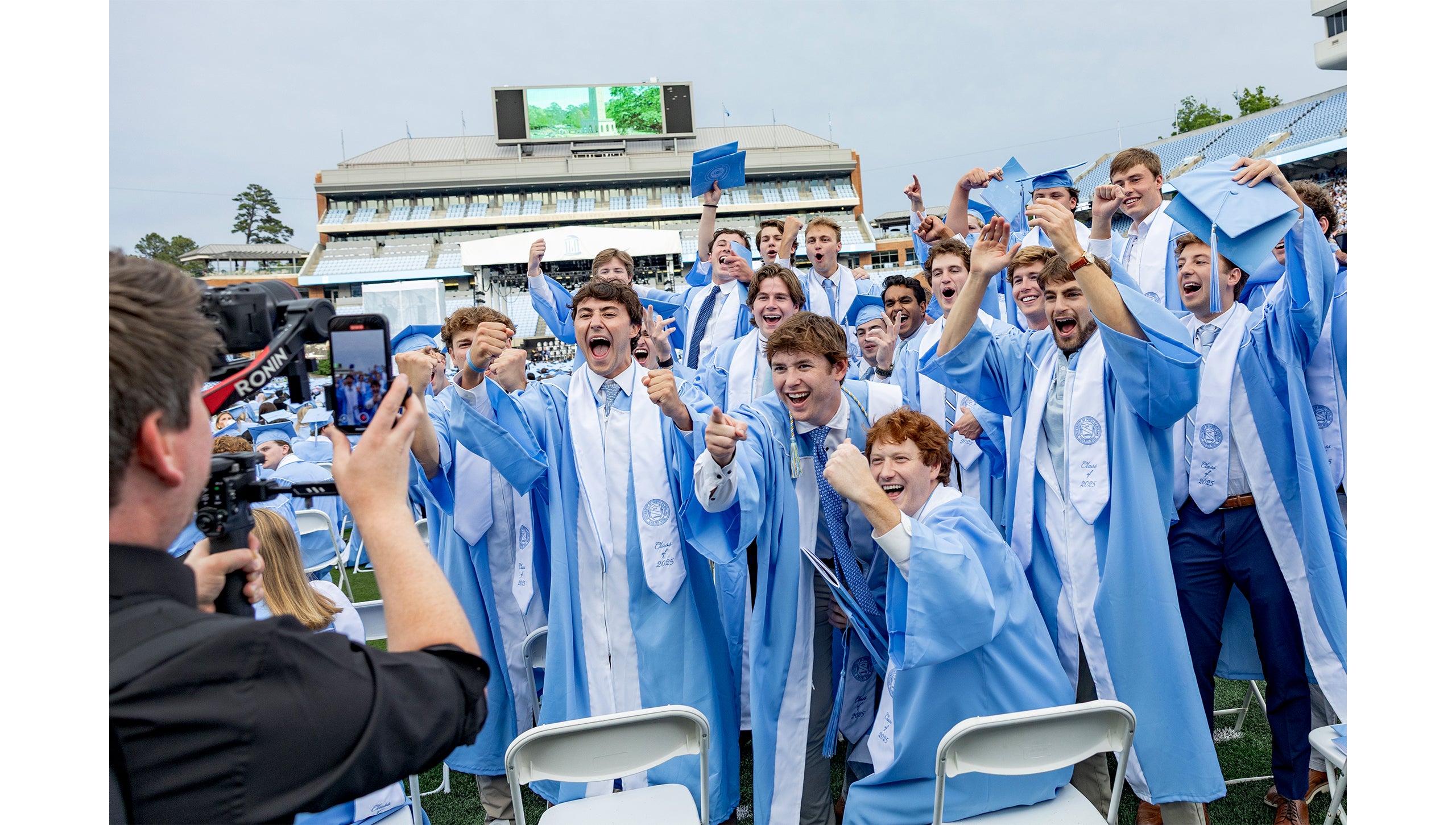 Graduates pose on the field before Spring Commencement