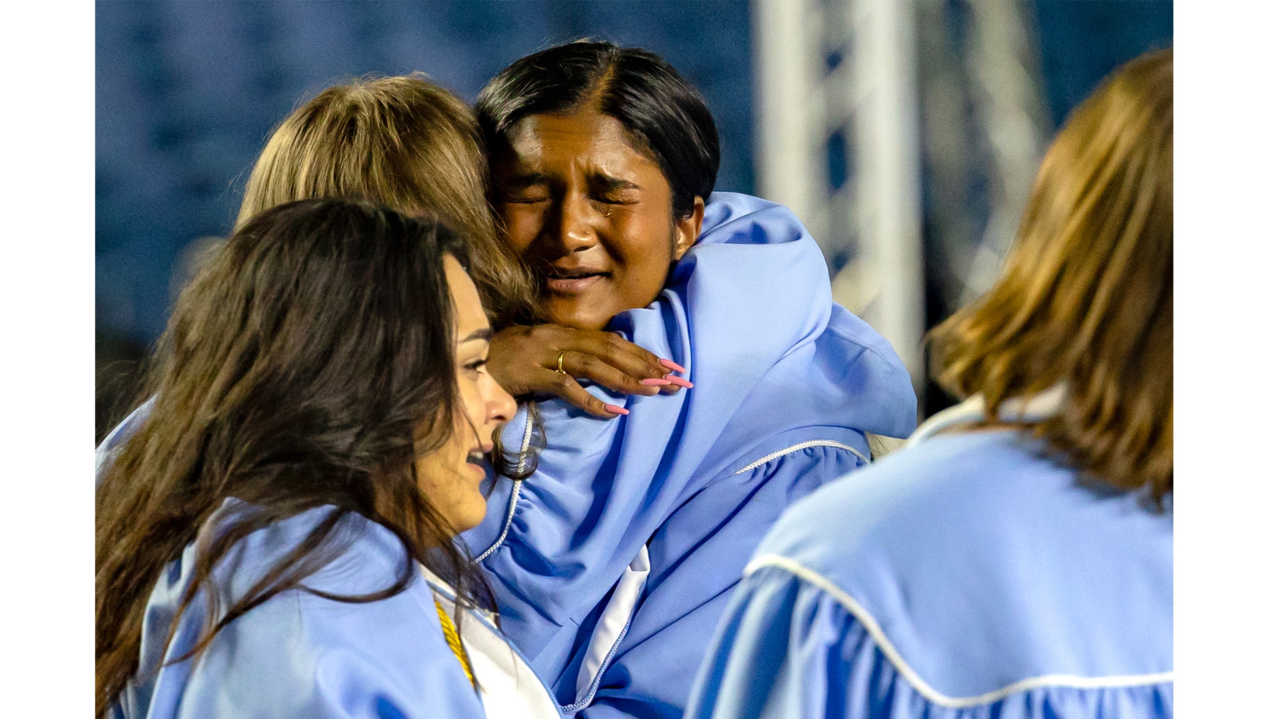 Graduates hug and cry on the field after Spring Commencement
