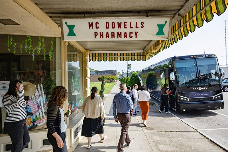 Attendees of the Tar Heel Bus Tour leaving McDowell's Pharmacy to get back on the bus.