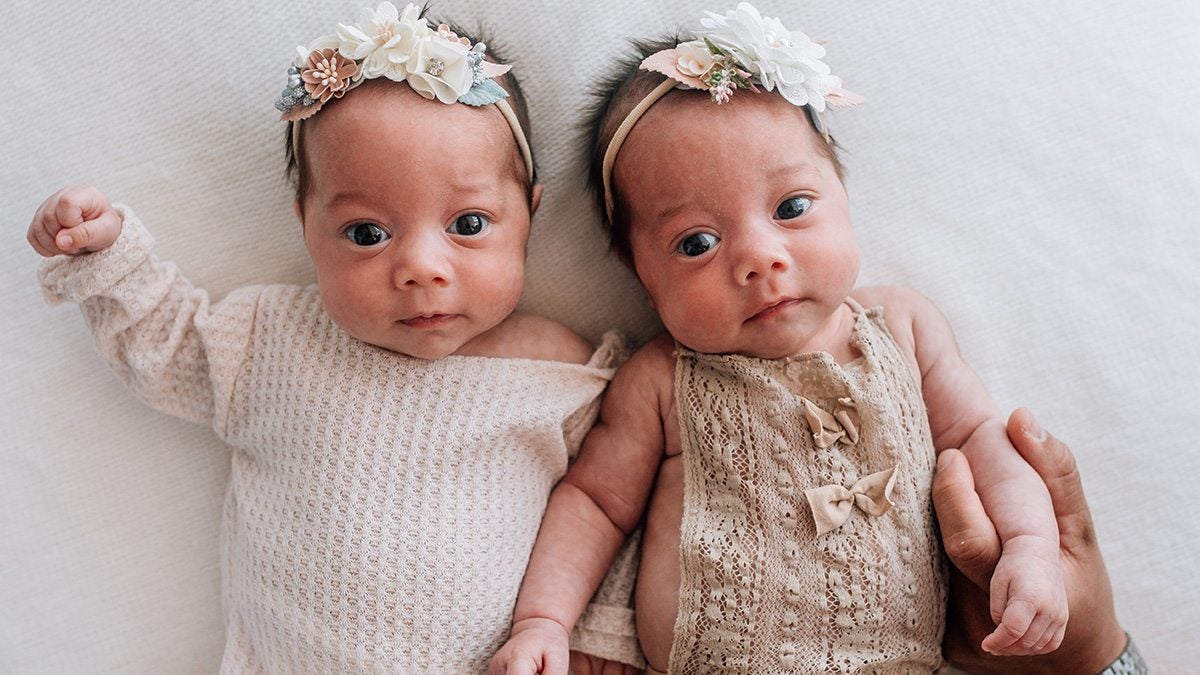 Twins, Isabella and Gabriella laying together looking at the camera.