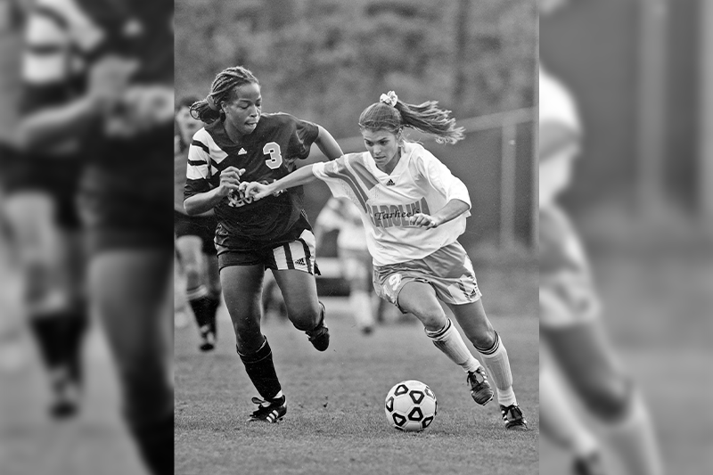 Mia Hamm dribbling past a defender in a UNC women's soccer game.