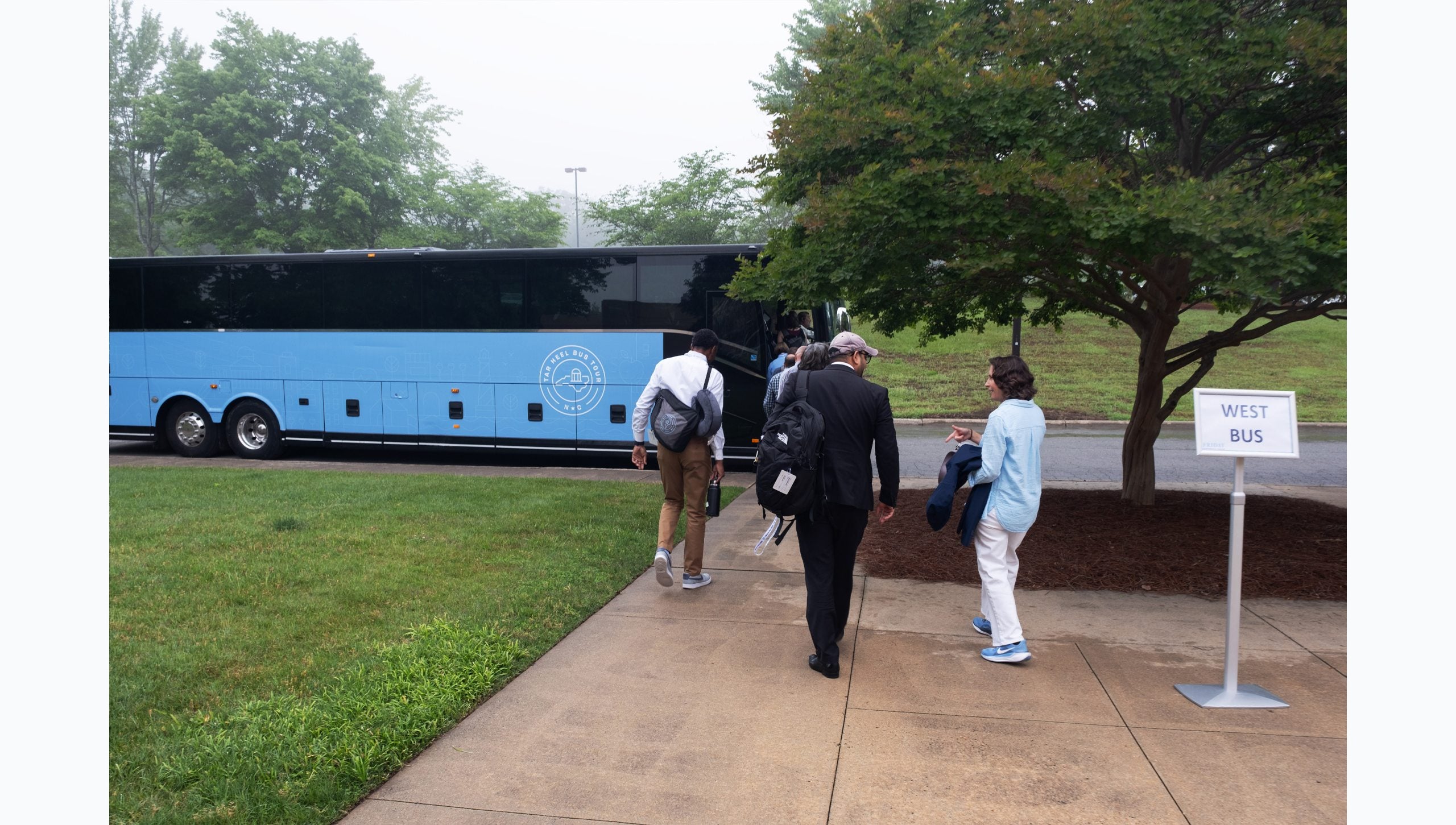 UNC-Chapel Hill faculty boarding the Carolina Blue West bus for the Tar Heel Bus Tour