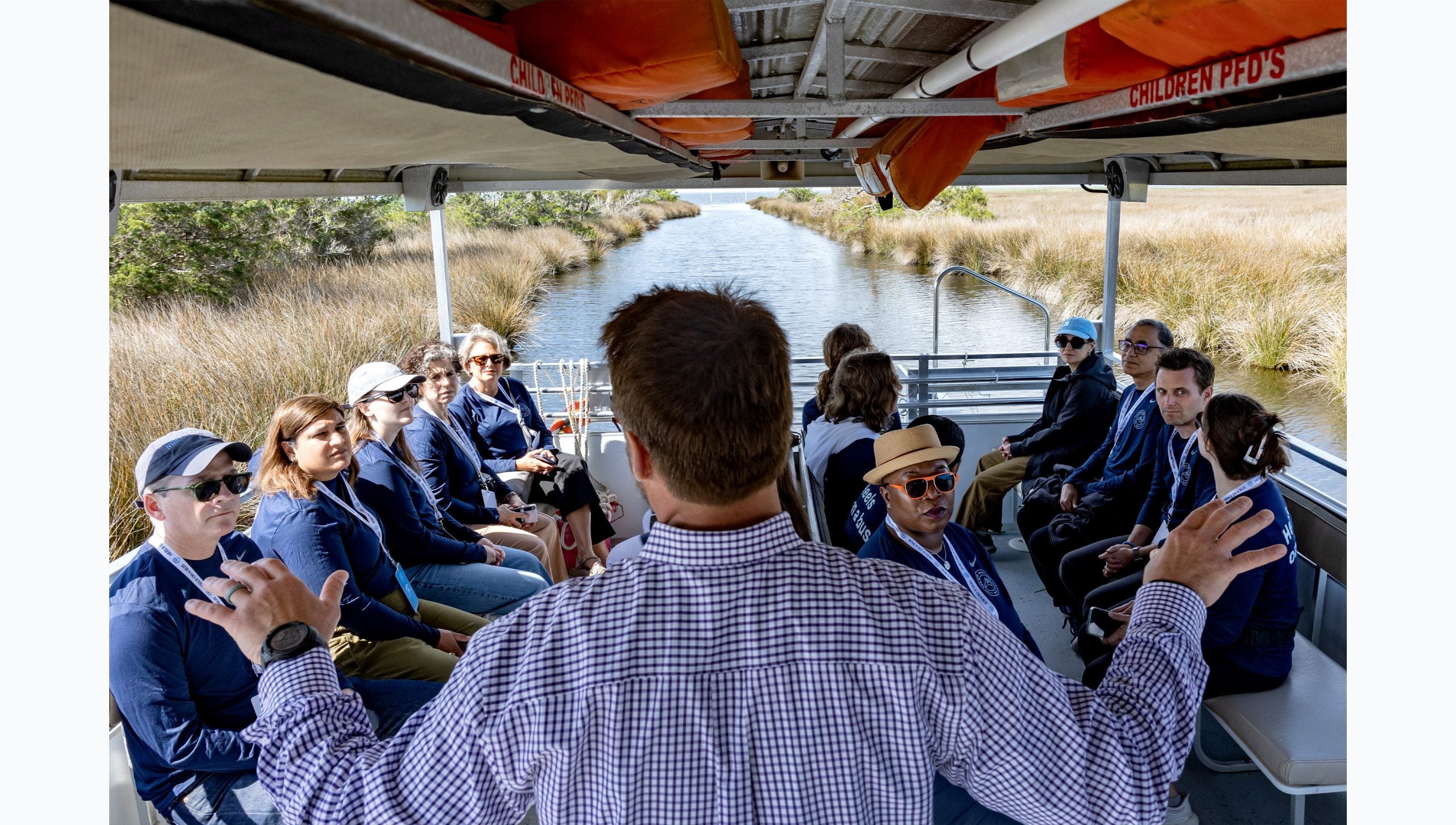 Tar Heel Bus Tour participants boarded on a boat in a marsh listening to a man speak.