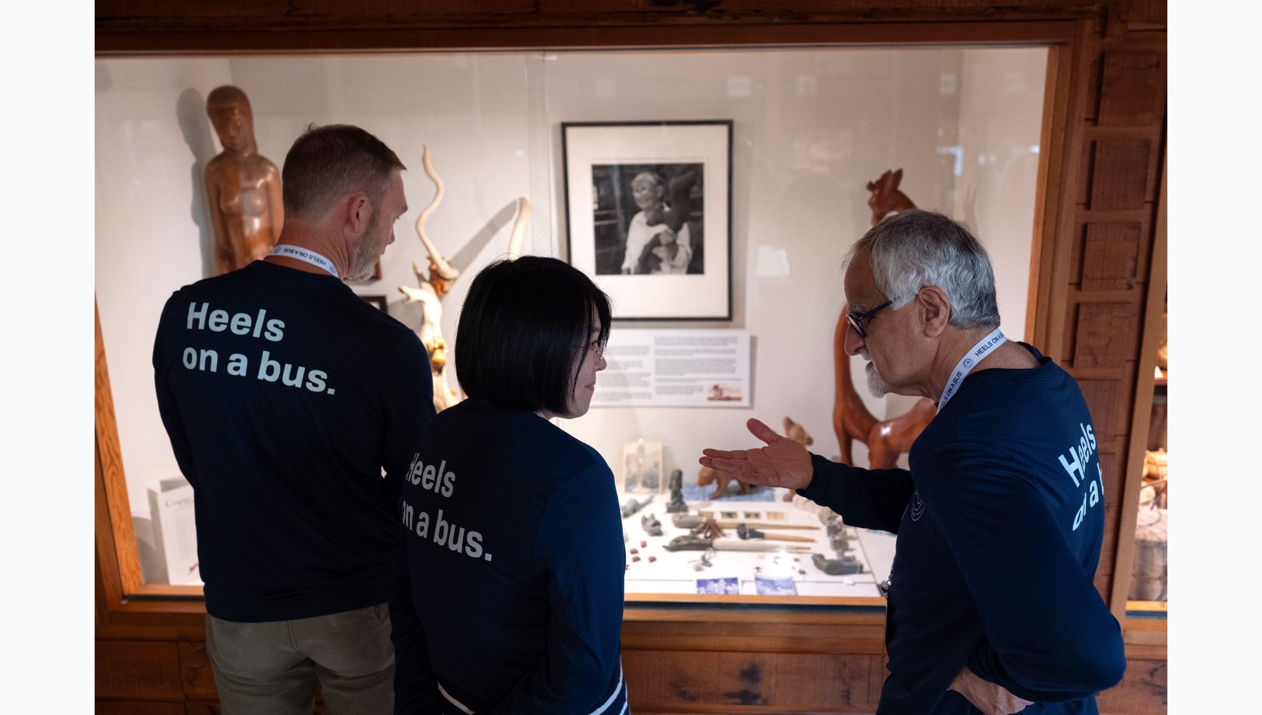 Three Tar Heel Bus Tour participants looking at museum display about Cherokee heritage and history.