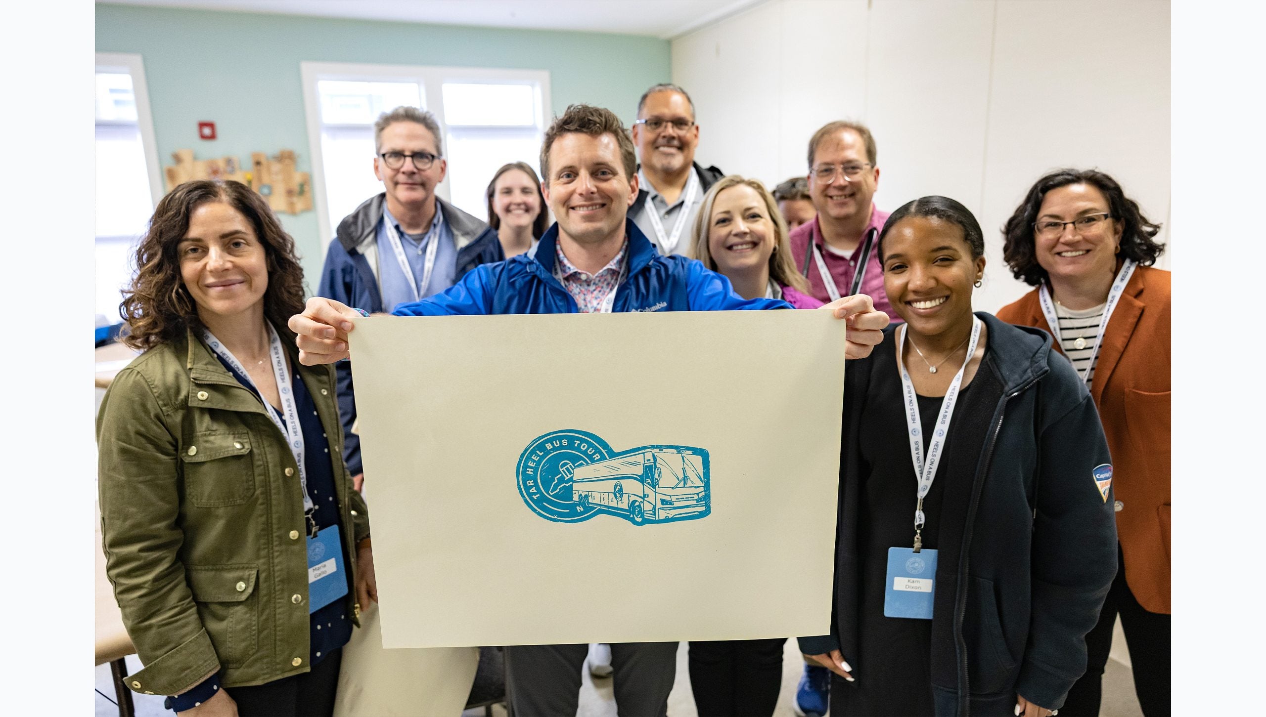 Tar Heel Bus Tour attendees passing holding and posing with a Tar Heel Bus Tour logo painting.