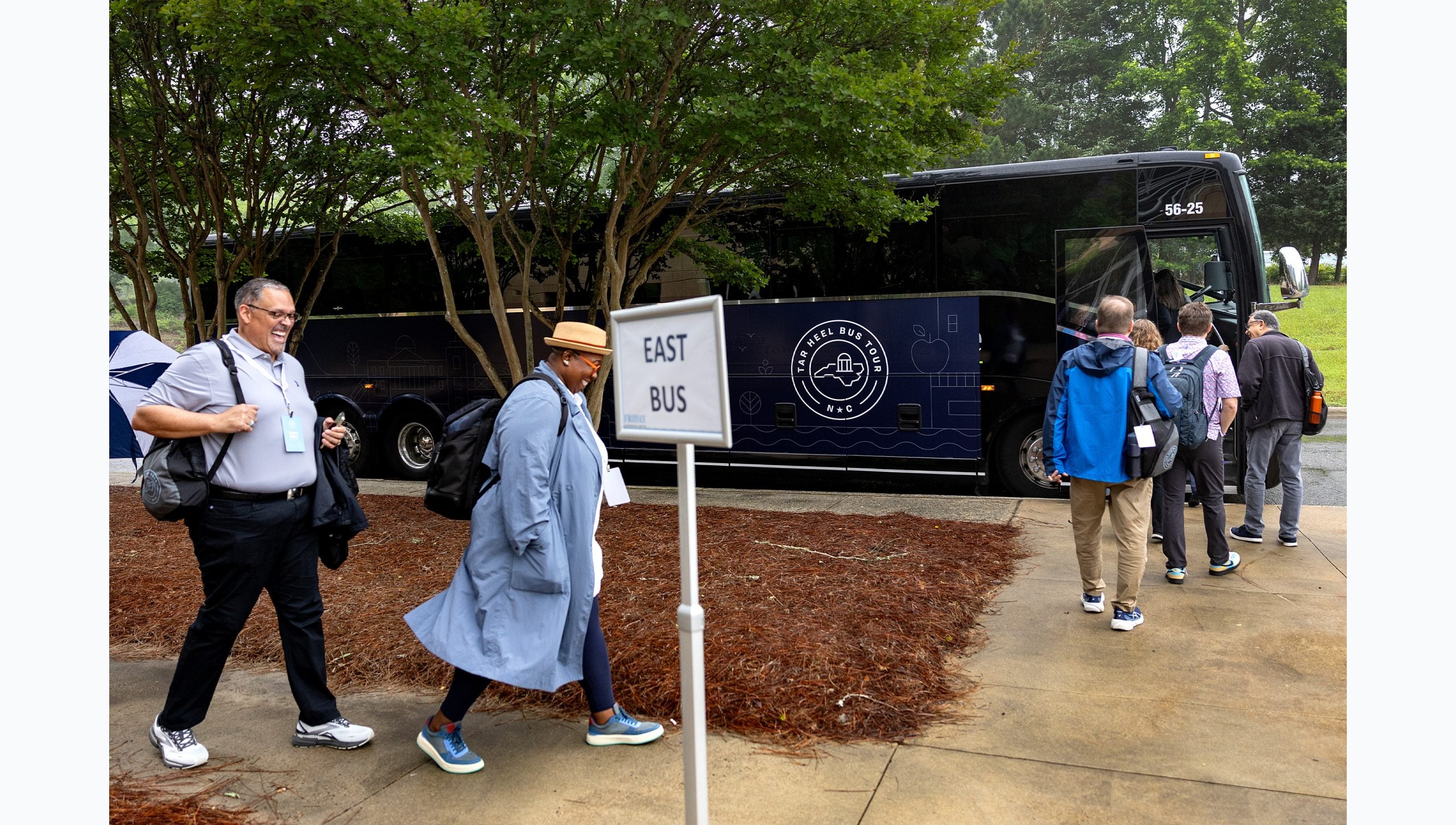 UNC-Chapel Hill faculty boarding the navy blue East Bus for Tar Heel Bus Tour
