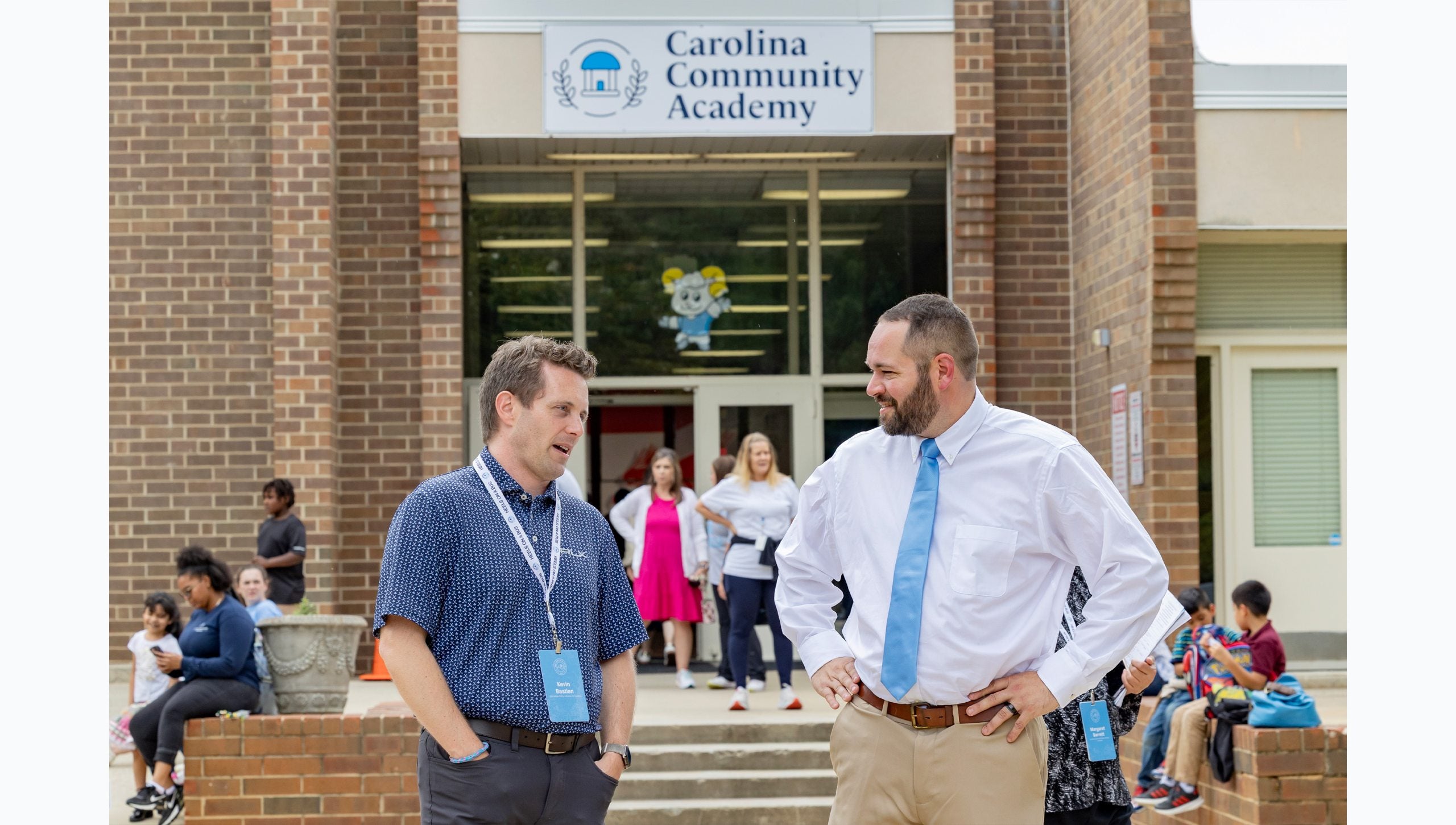 Two men, one a school administrator and the other an attendee of the Tar Heel Bus Tour, chatting outside Carolina Community Academy in Roxboro.