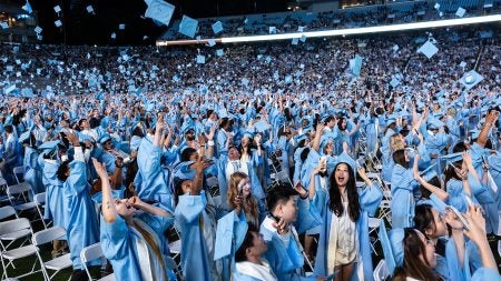 Graduates toss their caps at the end of Spring Commencement