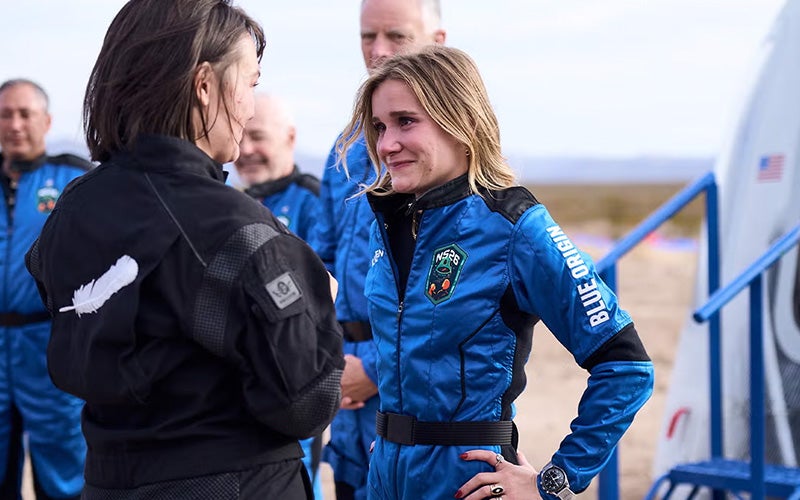 Karsen Kitchen, wearing an astronaut uniform, talks with a person before heading to space.